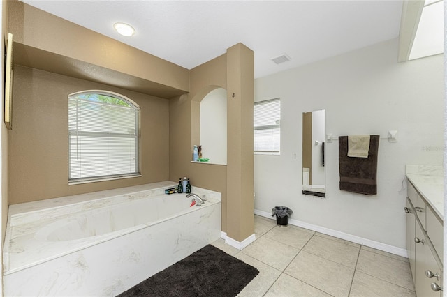 bathroom featuring tile patterned flooring, vanity, and a tub to relax in