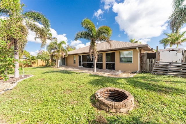 back of house featuring a patio area, a yard, and a fire pit