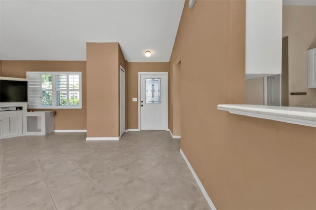 entryway featuring light tile patterned floors, vaulted ceiling, and plenty of natural light