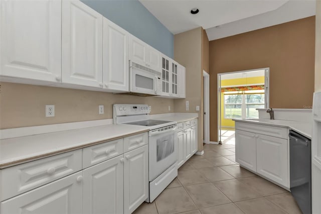 kitchen with white cabinetry, sink, light tile patterned floors, and white appliances