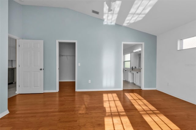 unfurnished bedroom with a spacious closet, connected bathroom, and light hardwood / wood-style flooring