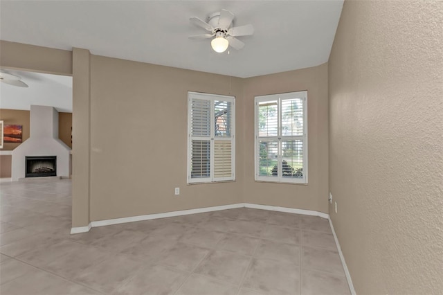 unfurnished room with ceiling fan and a large fireplace