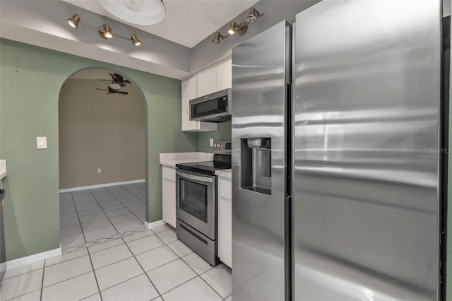 167 Mocha Ct, Punta Gorda, FL 33983 - kitchen with stainless steel appliances, arched walkways, white cabinetry, light tile patterned floors, and light countertops