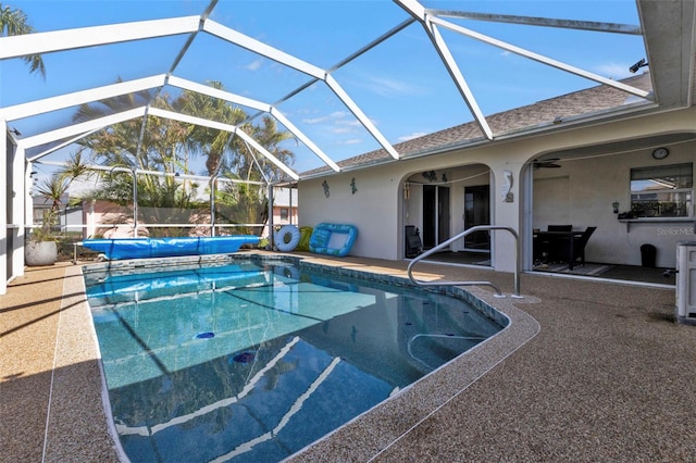 view of pool with glass enclosure and a patio