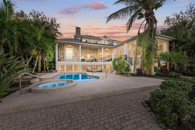 pool at dusk with a patio area, an in ground hot tub, and ceiling fan