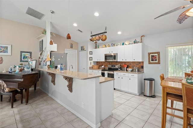 kitchen with pendant lighting, white cabinets, appliances with stainless steel finishes, decorative backsplash, and kitchen peninsula