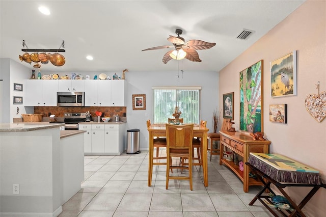 kitchen featuring ceiling fan, appliances with stainless steel finishes, tasteful backsplash, light tile patterned flooring, and white cabinets