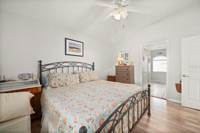 bedroom featuring ceiling fan, connected bathroom, hardwood / wood-style flooring, and lofted ceiling