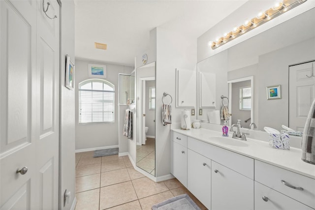 bathroom with tiled shower, tile patterned floors, vanity, and toilet