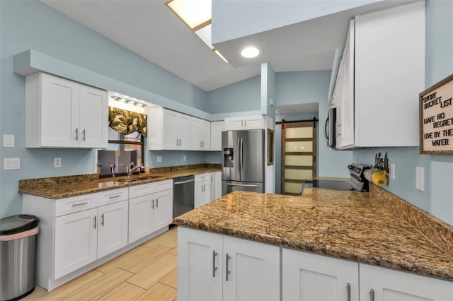 kitchen featuring kitchen peninsula, appliances with stainless steel finishes, sink, white cabinets, and lofted ceiling