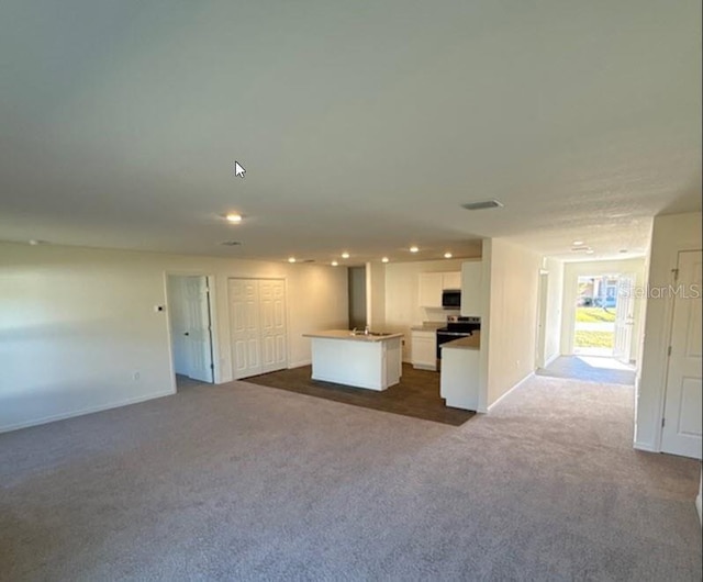 kitchen with white cabinets, a center island, stainless steel appliances, and dark colored carpet