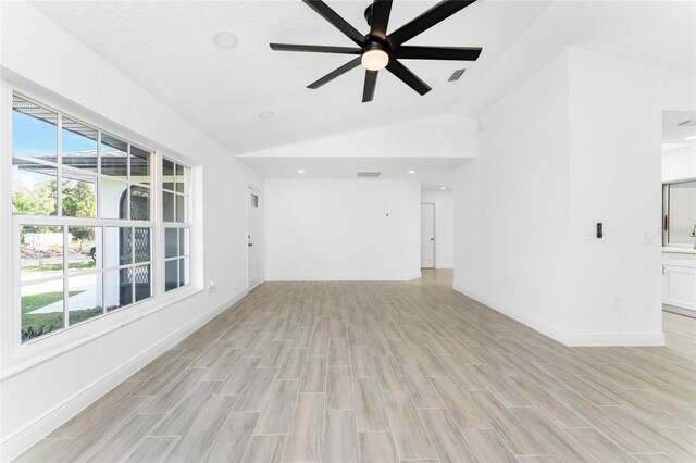 unfurnished living room featuring a textured ceiling, light wood-type flooring, vaulted ceiling, and ceiling fan