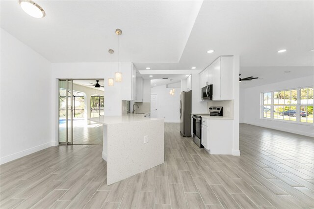 kitchen featuring kitchen peninsula, stainless steel appliances, pendant lighting, light hardwood / wood-style flooring, and white cabinetry