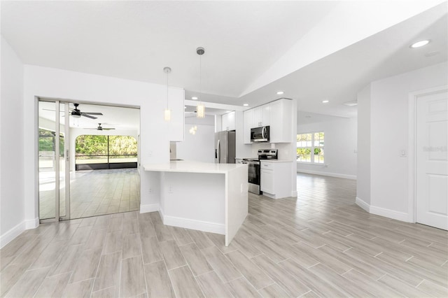 kitchen featuring kitchen peninsula, stainless steel appliances, pendant lighting, light hardwood / wood-style floors, and white cabinetry