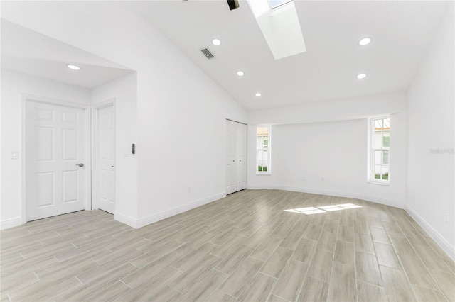 unfurnished room featuring light hardwood / wood-style floors, lofted ceiling with skylight, and a healthy amount of sunlight