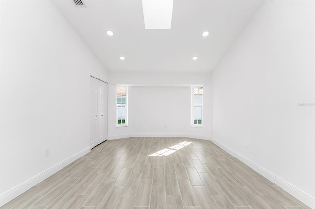 empty room featuring vaulted ceiling and light hardwood / wood-style floors