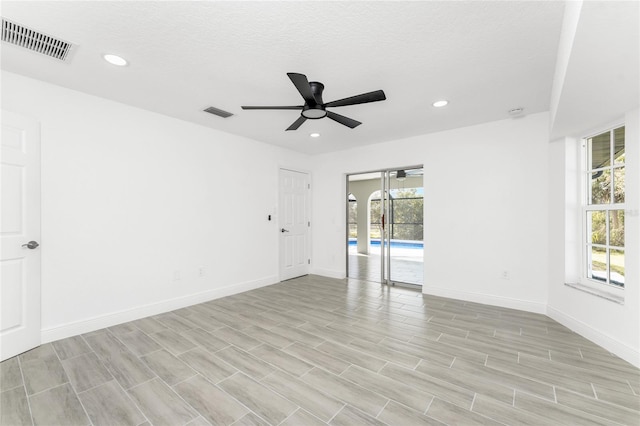 empty room with a textured ceiling, light hardwood / wood-style floors, and ceiling fan