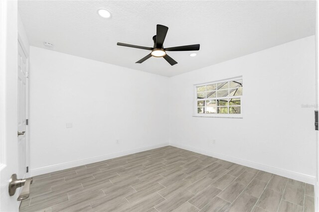 spare room featuring ceiling fan, light hardwood / wood-style floors, and a textured ceiling