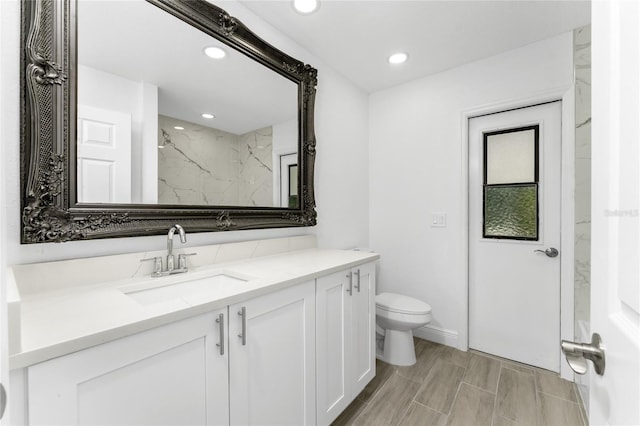 bathroom featuring tiled shower, vanity, and toilet