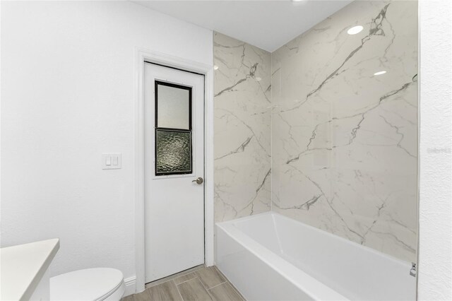 bathroom with toilet and tiled shower / bath