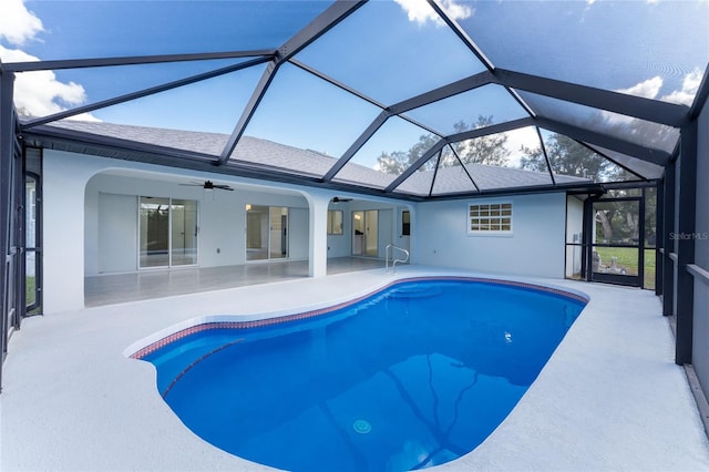 view of swimming pool with glass enclosure, ceiling fan, and a patio area