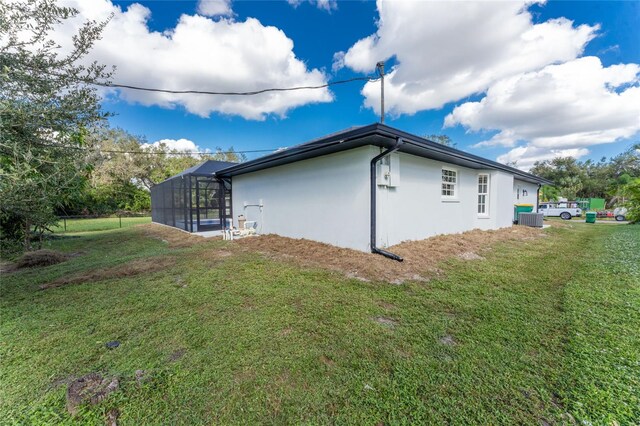 view of side of home with central AC, a yard, and a lanai