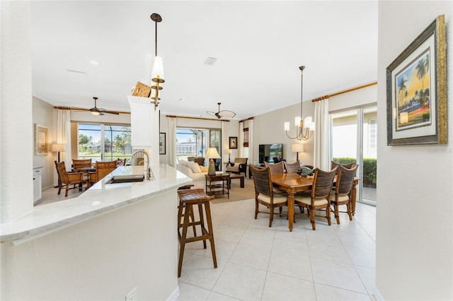 tiled dining area featuring ceiling fan with notable chandelier, ornamental molding, and sink