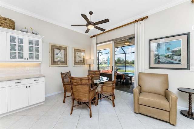 dining space with crown molding, light tile patterned flooring, and ceiling fan