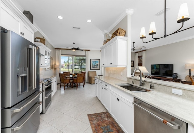 kitchen featuring ceiling fan with notable chandelier, stainless steel appliances, ornamental molding, and sink