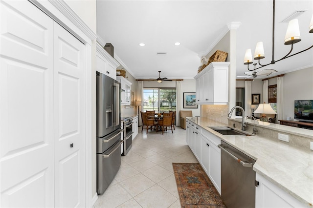 kitchen with ornamental molding, ceiling fan with notable chandelier, stainless steel appliances, decorative light fixtures, and white cabinets