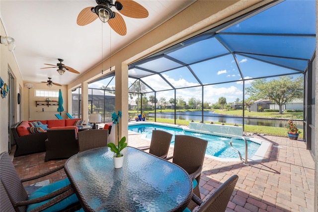 view of pool featuring outdoor lounge area, pool water feature, a water view, glass enclosure, and a patio area