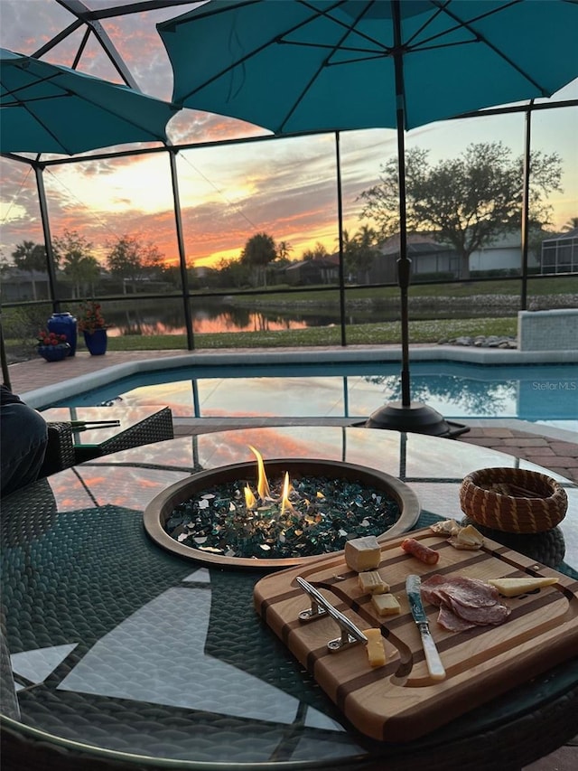 pool at dusk with glass enclosure and an outdoor fire pit