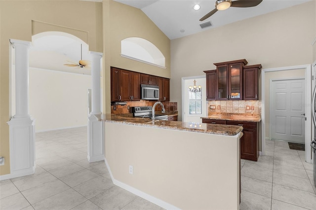 kitchen featuring high vaulted ceiling, light tile patterned floors, ornate columns, kitchen peninsula, and stainless steel appliances