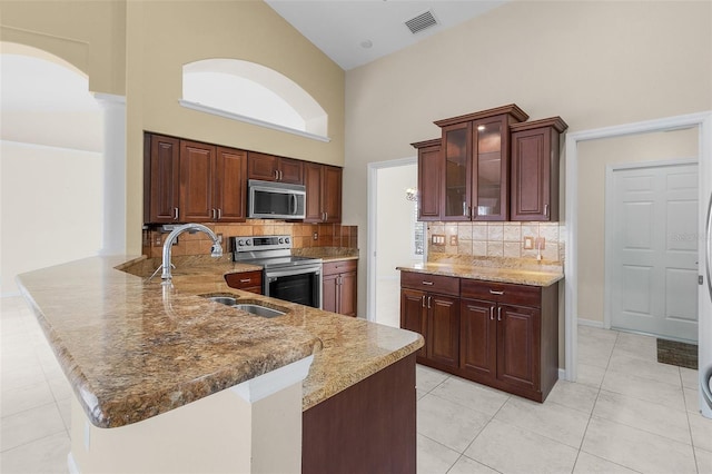 15460 Longview Rd, Port Charlotte, FL 33981 - kitchen with appliances with stainless steel finishes, a towering ceiling, a peninsula, tasteful backsplash, and glass insert cabinets