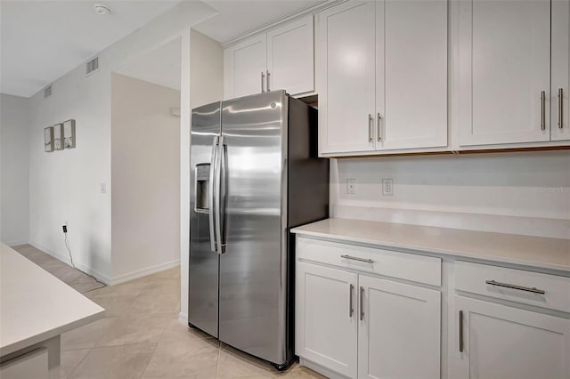 kitchen featuring white cabinetry, stainless steel fridge, and light tile patterned flooring