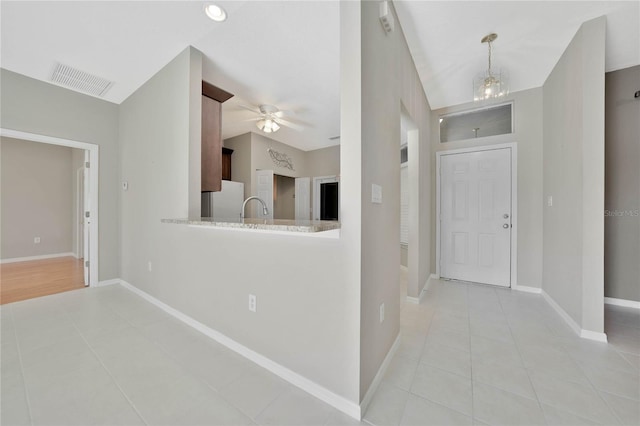 tiled foyer entrance featuring ceiling fan with notable chandelier and sink