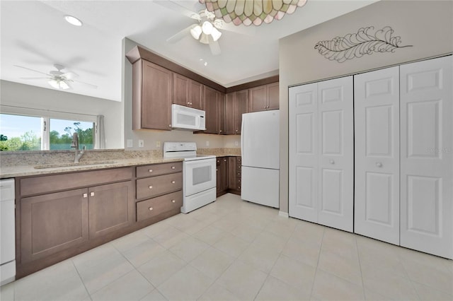 kitchen with white appliances, ceiling fan, light stone countertops, and sink