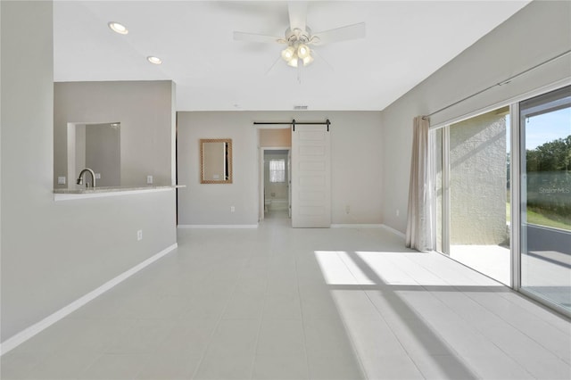 empty room featuring a barn door, ceiling fan, and sink