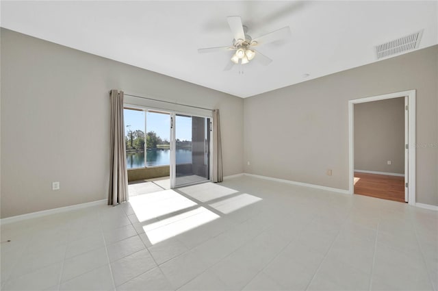 tiled empty room with ceiling fan and a water view