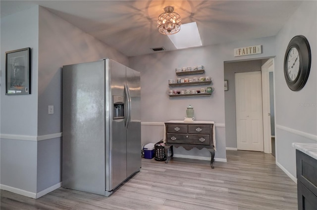 kitchen with a skylight, stainless steel fridge, and light hardwood / wood-style floors