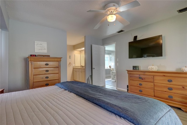 bedroom with ensuite bath, ceiling fan, and a textured ceiling