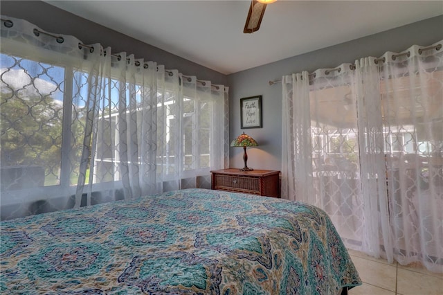 bedroom featuring ceiling fan, multiple windows, and tile patterned floors