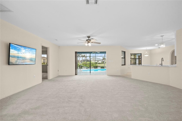 unfurnished living room with ceiling fan, light colored carpet, and sink