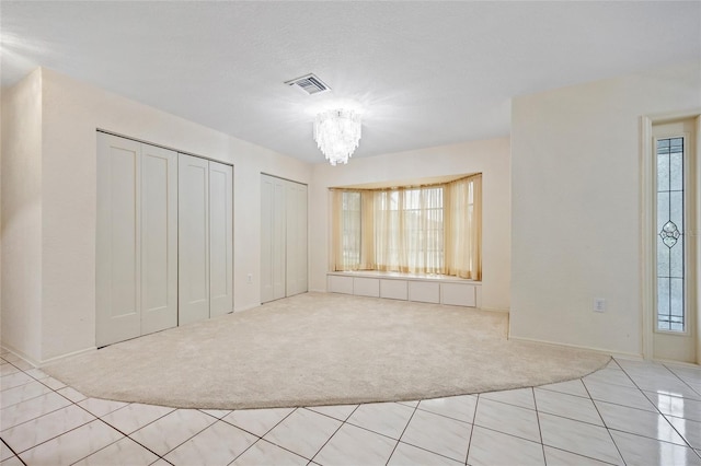 carpeted spare room featuring a chandelier