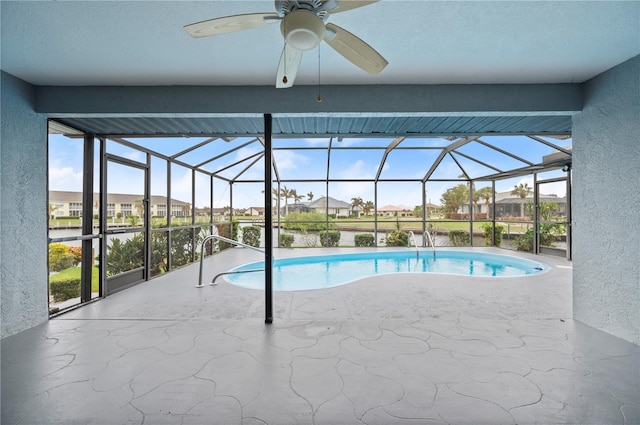 view of pool featuring a patio area, ceiling fan, glass enclosure, and a water view