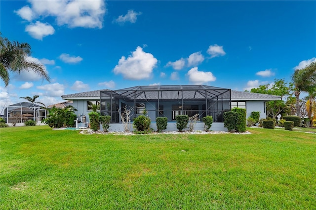 back of property with glass enclosure and a yard