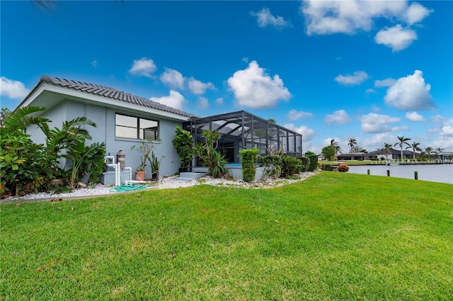 back of house with a lanai, a lawn, and a water view