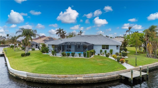 rear view of property with a swimming pool, a water view, glass enclosure, and a lawn