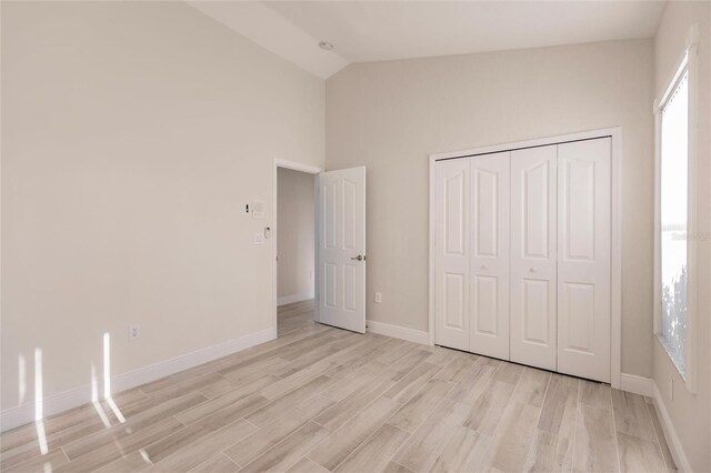 17183 Ohara Dr, Port Charlotte, FL 33948 - unfurnished bedroom featuring light wood-type flooring, baseboards, high vaulted ceiling, and a closet