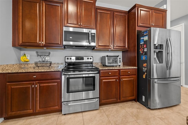 kitchen with appliances with stainless steel finishes, light stone countertops, and light tile patterned floors